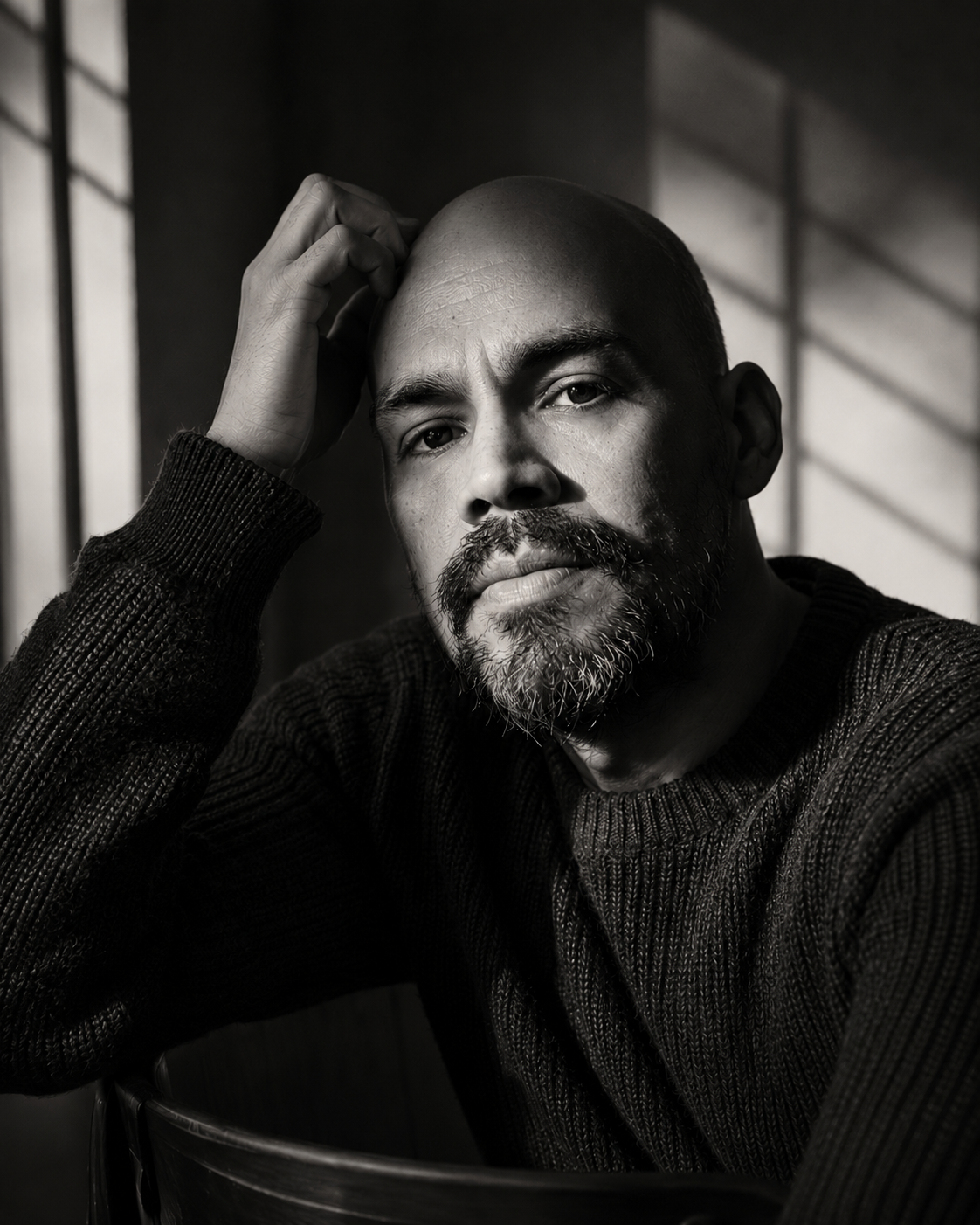 Black and white portrait of Daniel Lord resting his hand on his head in window light